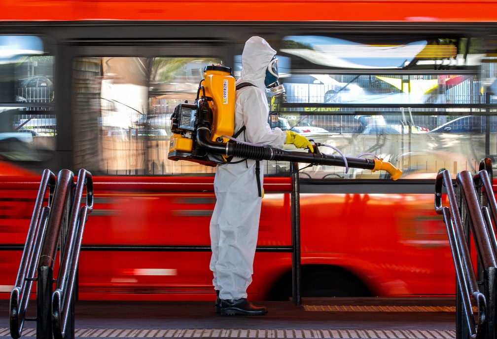 Membro das Forças Armadas joga desinfetante no Terminal Santa Cândida, em Curitiba, no dia 10 de agosto, para evitar disseminação do novo coronavírus (Sars-CoV-2). — Foto: Daniel Castellano/AFP