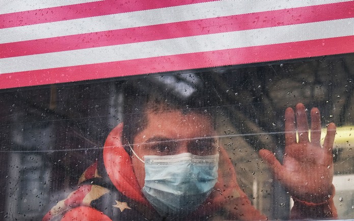 Homem com máscara acena da janela de um ônibus em Queens, Nova York, região que tem uma das maiores incidências de contágio por coronavírus nos EUA, na sexta-feira (3) — Foto: Spencer Platt/Getty Images/AFP 