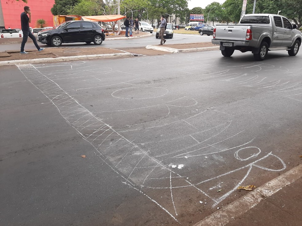 Ambulante escreve com giz "Pare por favor" em pista com faixa de pedestre apagada, na Asa Sul.  — Foto: Aline Ramos/G1 