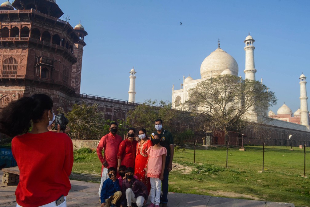 Visitantes usam máscaras são fotografados fora do Taj Mahal após o seu fechamento em Agra, nesta terça-feira (17) — Foto: Pawan Sharma / AFP