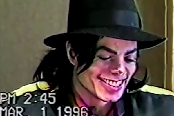 O cantor Michael Jackson (1958-2009) sorrindo em meio ao depoimento dele no ano de 1996 sobre as acusações de abusos de menores (Foto: Reprodução)