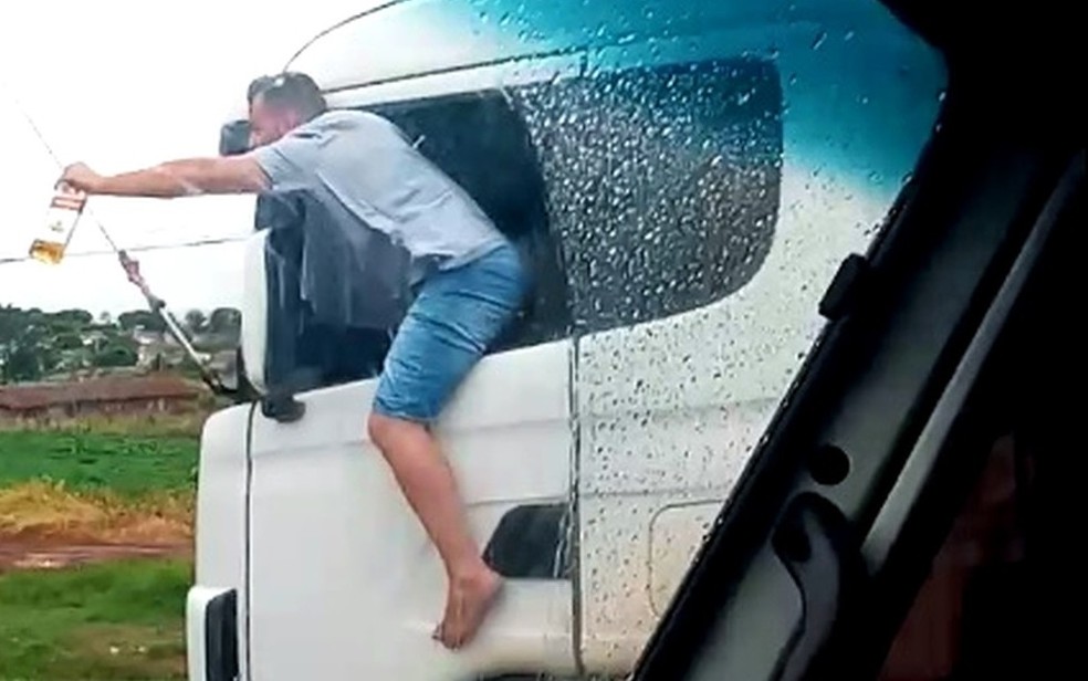 Caminhoneiro é filmado com corpo para fora de veículo com garrafa de bebida na mão enquanto dirige no Paraná — Foto: Divulgação