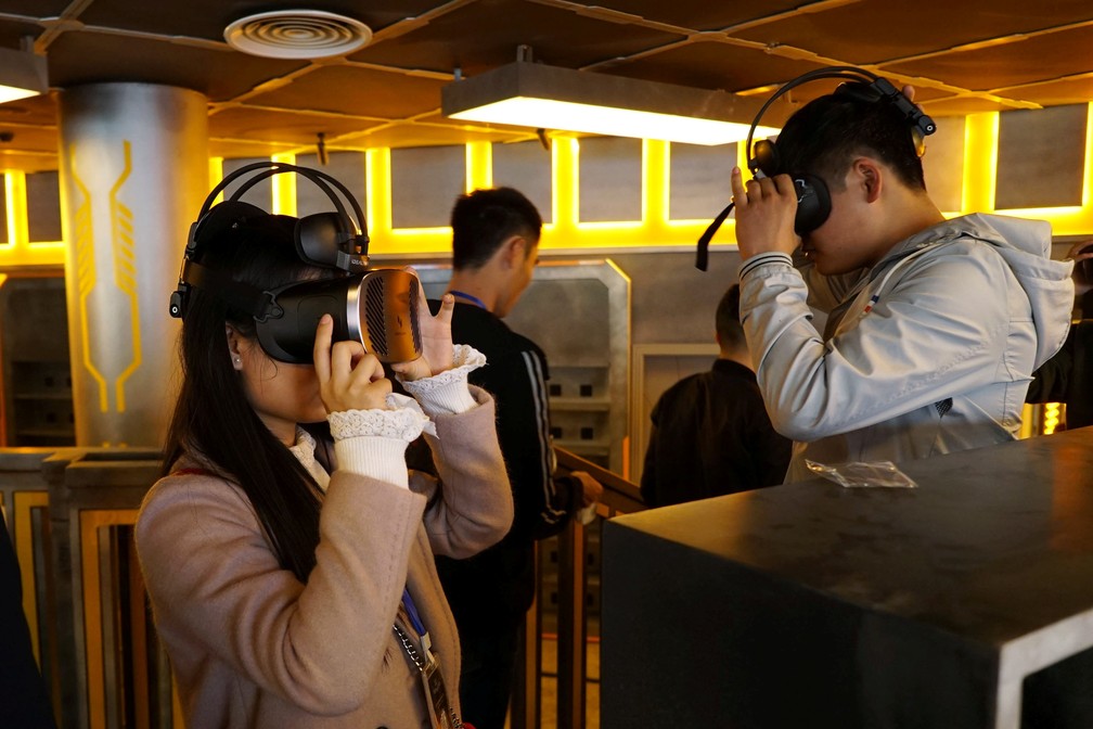 Visitantes usam óculos de realidade virtual em parque temático na província Guizhou, na China. (Foto: Joseph Campbell/Reuters)