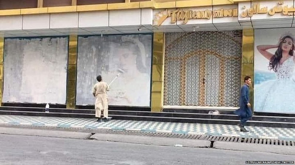 Homem cobre de tinta fotos de mulheres pintadas em muro de Cabul — Foto: Lotfullah Najafizada/Twitter
