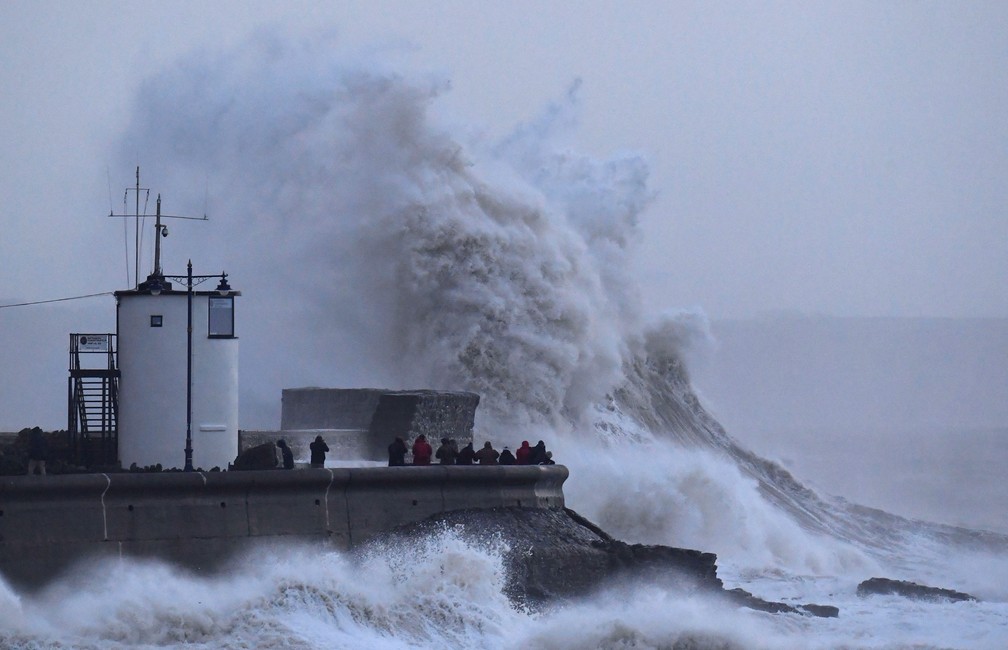 3 de janeiro - Pessoas são vistas ao lado de ondas gigantes e ventos fortes associados com a tempestade Eleanor no farol e paredão em Porthcawl, no sul do País de Gales (Foto: Toby Melville/Reuters)
