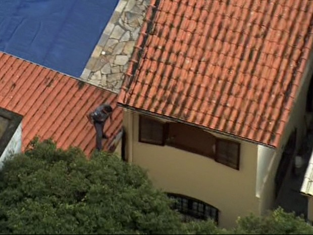 PM sobe no telhado para observar a movimentação dos bandidos (Foto: Reprodução/TV Globo)