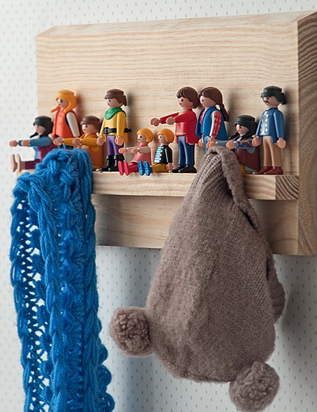 Os bonecos de Playmobil foram resgatados entre os brinquedos e fixados com cola quente a uma tábua de madeira. Ora sentados, ora em pé, eles acomodam roupas e chapéus
