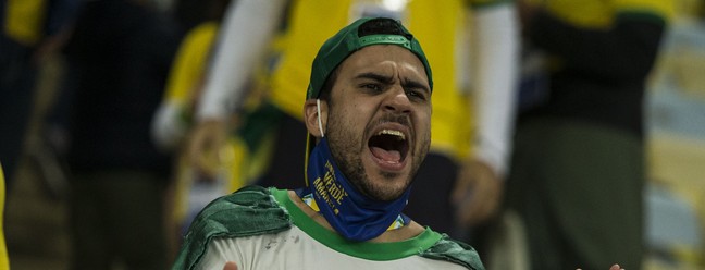 Torcedor com máscara de proteção no queixo grita da arquibancada antes da final da Copa América entre Brasil e Argentina, no MaracanãAgência O Globo