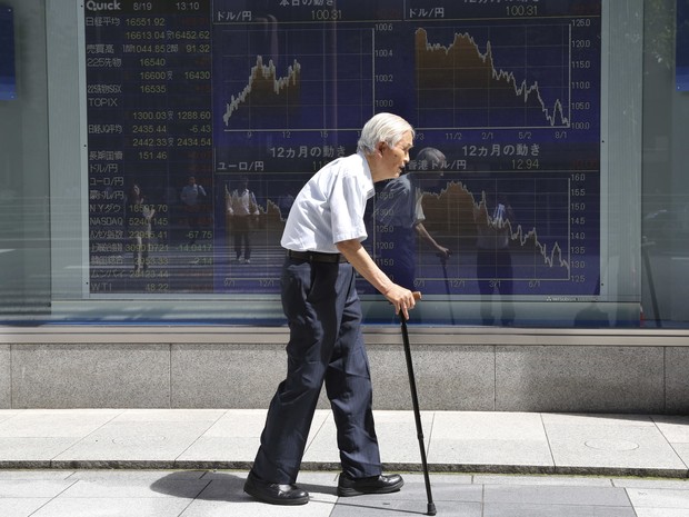 日本の東京で金融市場の相場の前を歩く老人（写真：AP Photo/Kojiasahara）