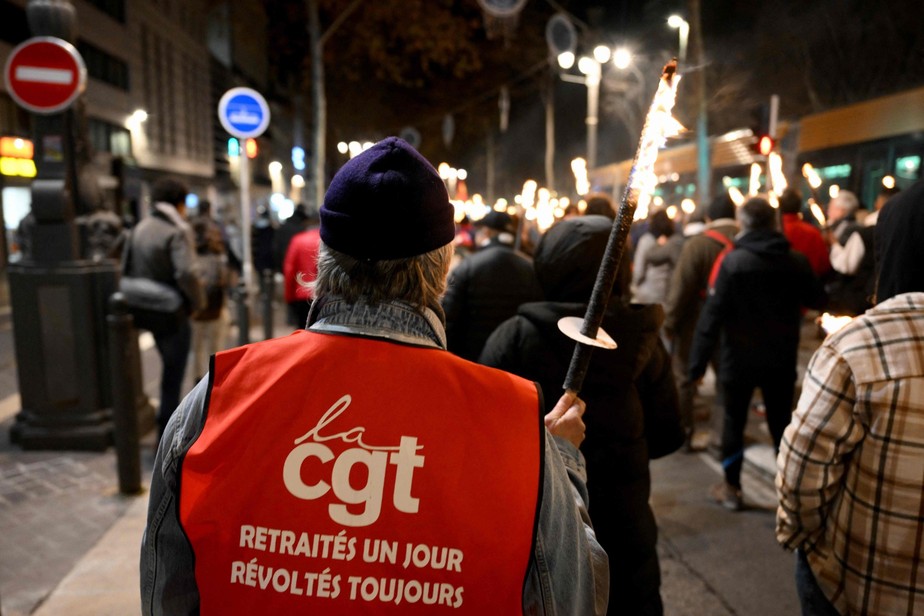 Manifestante da central sindical CGT caminha carregando tocha em Marselha em protesto contra reforma da Previdência