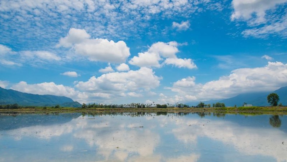 Campo de arroz em Taiwan: sob um céu azul com nuvens, um campo alagado refletindo a paisagem — Foto: Getty Images via BBC