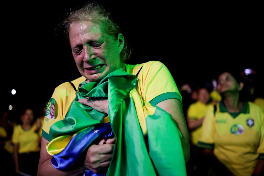 Em Brasília, eleitora de Bolsonaro chora abraçada à bandeira do Brasil — Foto: REUTERS/Ueslei Marcelino