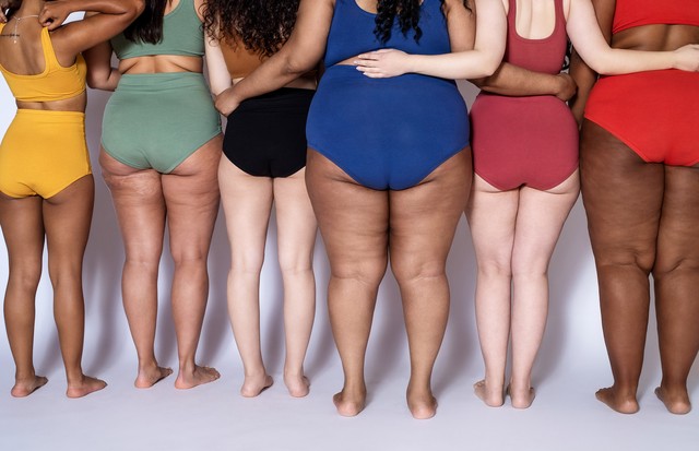 Rear view of group of women with different body type in underwear standing together on white background. Cropped shot of diverse females in lingerie with their arms around each other. (Foto: Getty Images)