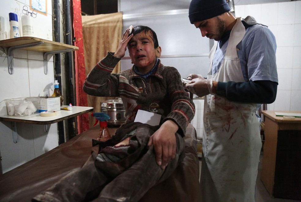 Garoto de 12 anos ferido recebe tratamento e aguarda notícias de sua mãe, que passa por cirurgia no mesmo hospital; eles foram vítimas de um bombardeio na região de Guta Oriental, perto de Damasco, na Síria, no dia 19 de fevereiro de 2018 (Foto: Ammar Suleiman/AFP)