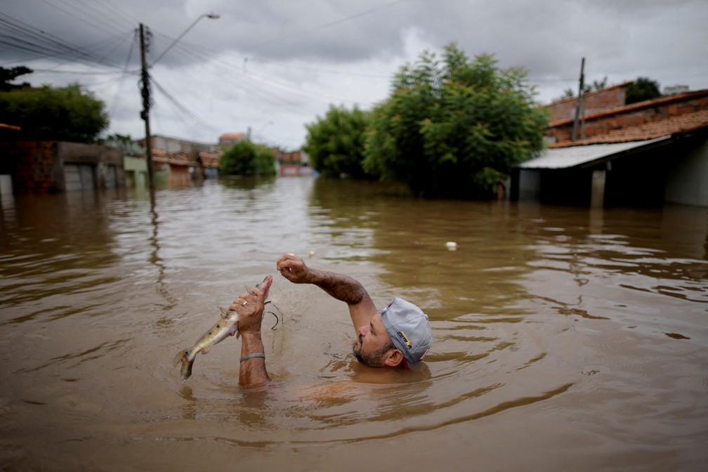 6 de janeiro - Homem pesca um peixe em uma rua alagada durante as enchentes causadas por fortes chuvas em Imperatriz, estado do Maranho — Foto: Ueslei Marcelino/Reuters