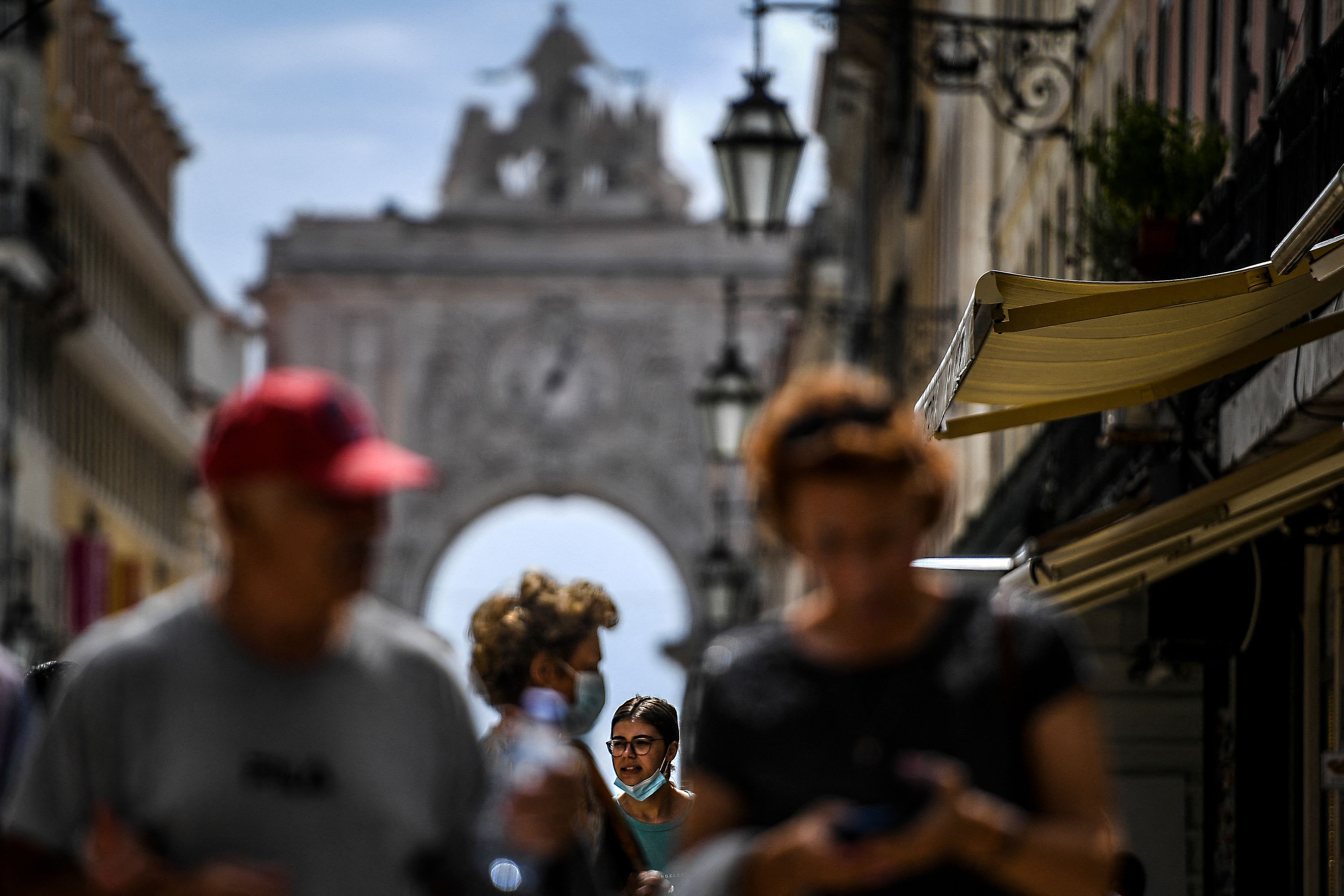 Pessoas com máscara e sem caminham pela baixa de Lisboa 