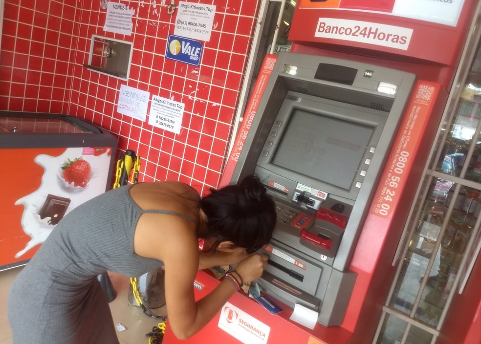 Estudante Naely Rodrigues tenta tirar notas emperradas em caixa eletrônico após saque no DF — Foto: Arquivo pessoal