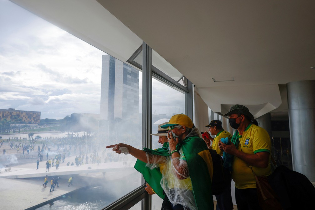 Radicais olham pela janela após invadirem o Palácio do Planalto — Foto: REUTERS/Adriano Machado
