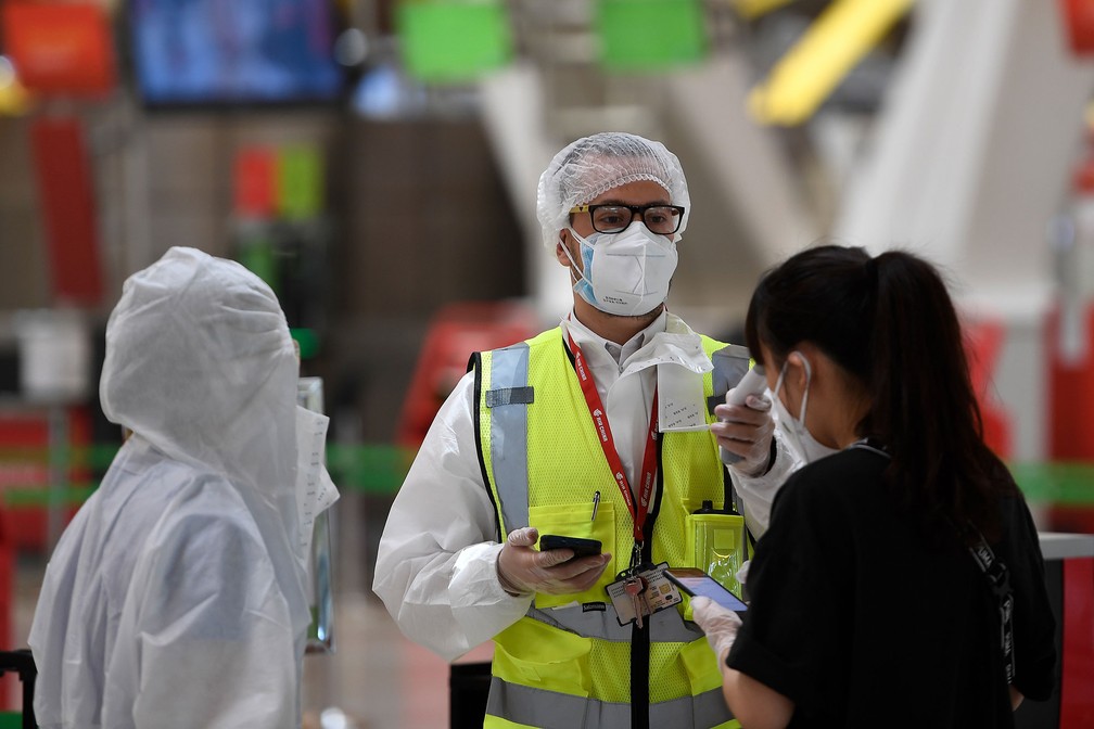 20 de junho - Funcionário de aeroporto de Barajas, em Madri, na Espanha, verifica temperatura de passageiros que vão embarcar em voo para Pequim — Foto: Pierre-Philippe Marcou/AFP