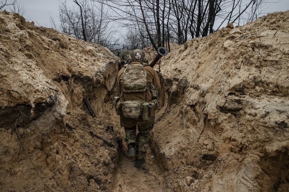 Soldado da 28ª Brigada Mecanizada Separada do Exército ucraniano atravessa uma trincheira durante ataque russo na região de Donetsk.