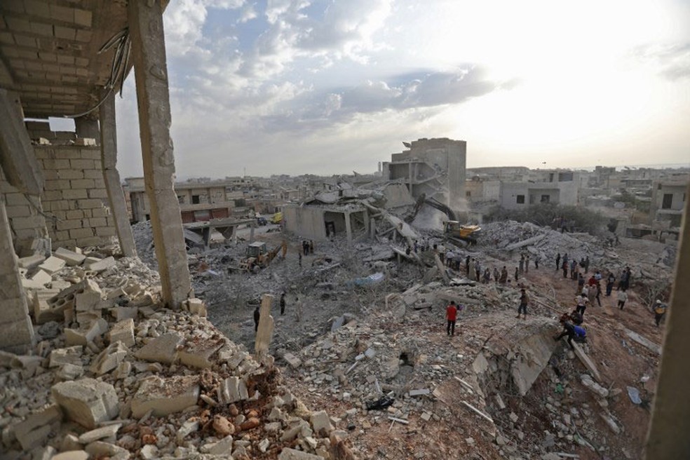 SÃ­rios caminham sobre destroÃ§os em Zardana, em Idlib, nesta sexta-feira (8)  (Foto: Omar Haj Kadour / AFP)