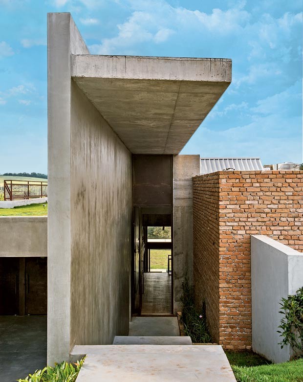 Entrada principal | A parede de concreto com laje em balanço protege o acesso à casa. À esq., o teto verde beneficia o conforto térmico (Foto: Edu Castello/Editora Globo)
