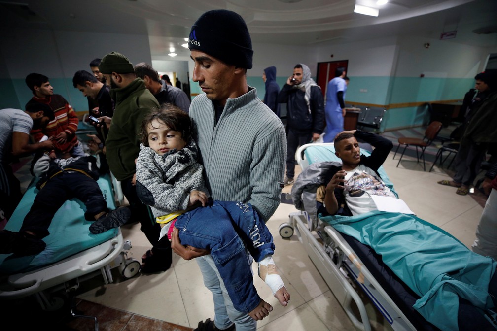 Homem carrega criança ferida por bombardeio israelense contra a Faixa de Gaza nesta sexta-feira (8) (Foto: Mohammed Salem/ Reuters)