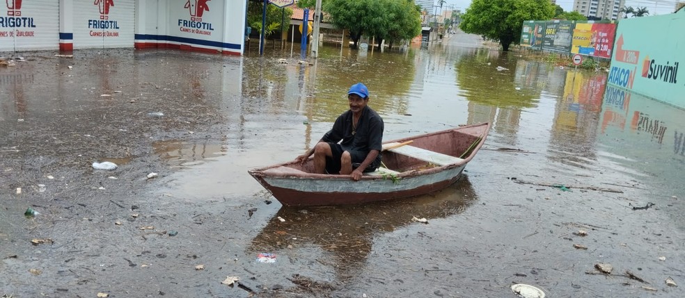 Morador precisou usar barco para atravessar via inundada após a chuva. — Foto: Claudiana Mourato/SVM