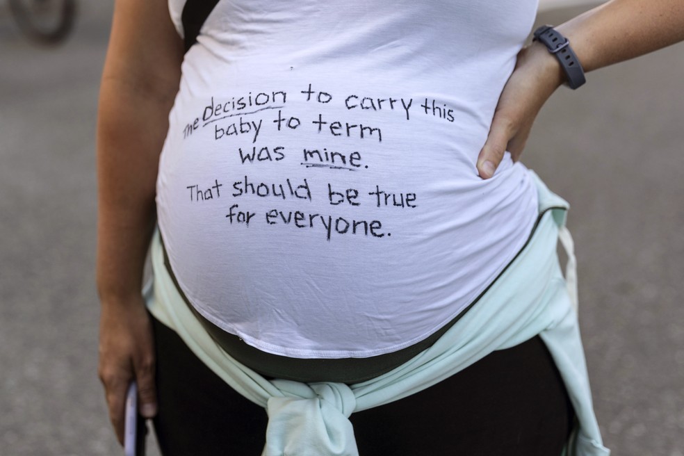 Foto mostra mulher grávida em protesto pelo direito ao aborto legal nos Estados Unidos em Seattle, Washington, na sexta-feira (24). Ela veste uma camiseta em que está escrito 'a decisão de ter esse bebê foi minha. Isso deveria ser verdade para todo mundo'. — Foto: Stephen Brashear/AP
