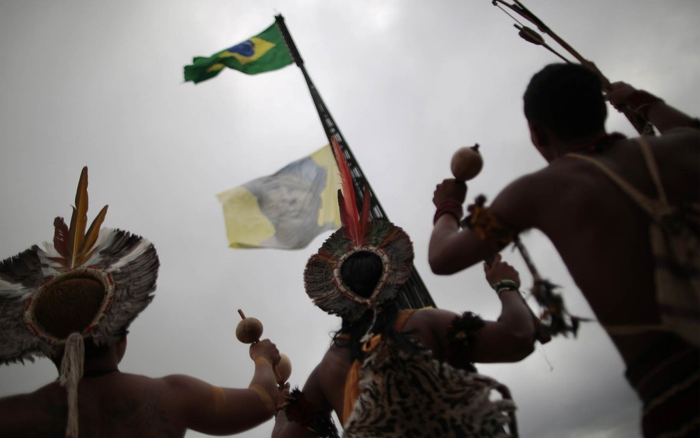 Índios de diferentes partes do Brasil observam uma bandeira com a imagem de um indígena ser erguida no mastro da Bandeira Nacional em Brasília, durante protesto em parceria com o Greenpeace contra a PEC que antera a lei de demarcação de terras. — Foto: Ueslei Marcelino/Reuters