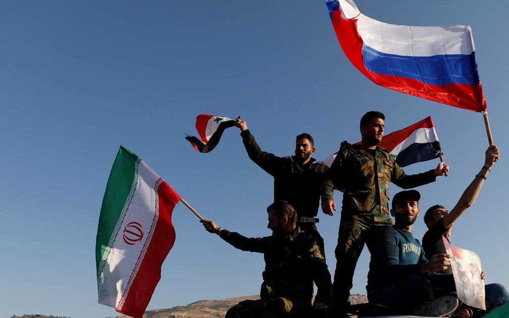 Sírios agitam bandeiras iranianas, russas e sírias durante protesto contra ataques aéreos liderados pelos EUA em Damasco (Foto: Omar Sanadiki / Reuters)