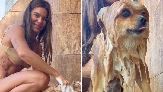 De biquíni, Mariana Goldfarb dá banho de chuveiro em cãozinho