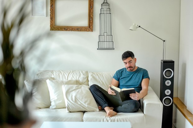 Man reading a book relaxing at home. Lockdown concept. (Foto: Getty Images/iStockphoto)