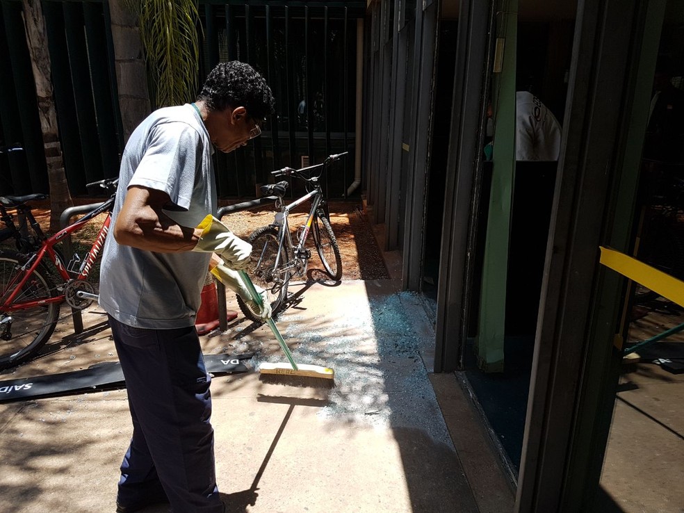 Funcionário da Câmara limpa vidro quebrado após confusão com índios (Foto: Marina Oliveira/G1)