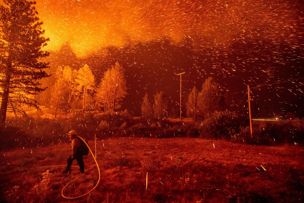 6 de setembro - Fagulhas são vistas sobre um bombeiro que trabalha no combate  ao incêndio conhecido localmente como 'Delta Fire' na floresta nacional Shasta-Trinity, na Califórnia, nos EUA — Foto: Noah berger/AP