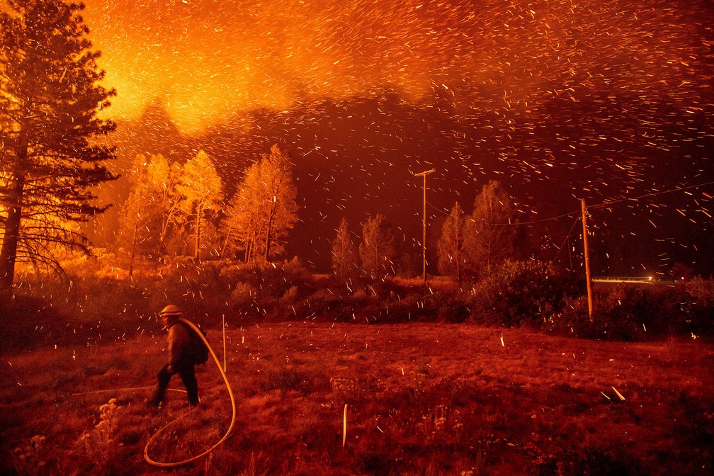6 de setembro - Fagulhas são vistas sobre um bombeiro que trabalha no combate  ao incêndio conhecido localmente como 'Delta Fire' na floresta nacional Shasta-Trinity, na Califórnia, nos EUA — Foto: Noah berger/AP
