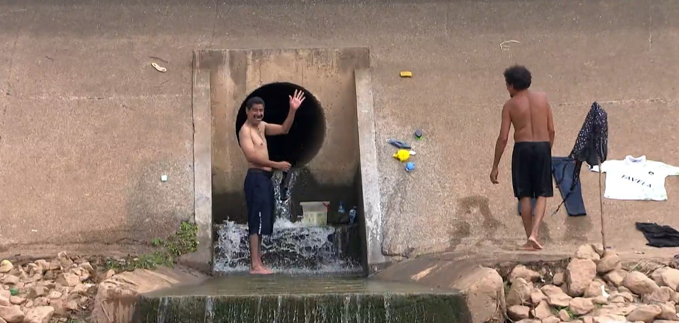 Homens tomam banho e lavam roupas em duto às margens do Rio Tietê em São Paulo