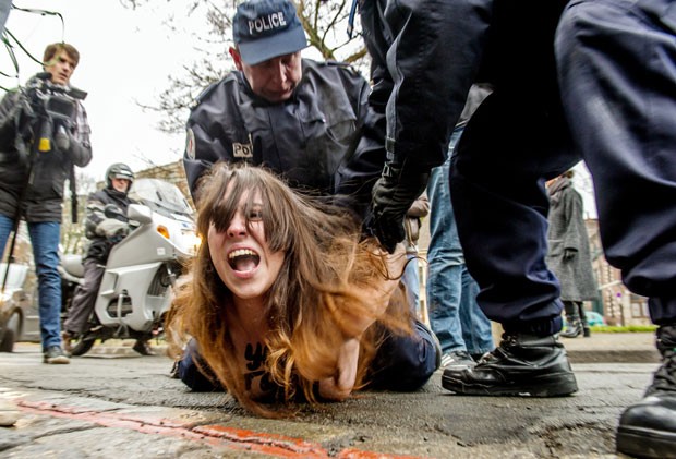 Policiais detêm ativista do Femen após ela pular sobre o carro de Dominique Strauss-Kahn, na chegada do ex-diretor do FMI ao seu julgamento em Lille nesta terça-feira (10) (Foto: Philippe Huguen/AFP)