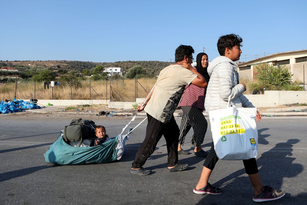 Um homem puxa um bebê enquanto migrantes do destruído campo de Moria, na ilha de Lesbos, na Grécia, seguem para um novo campo temporário nesta quinta-feira (17)  — Foto: Elias Marcou/Reuters 