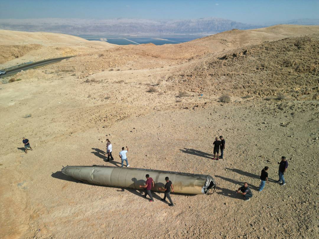 Pessoas olham carcaça de míssil iraniano no deserto perto da cidade de Arad, ao sul de Israel. Míssil foi utilizado em bombardeio contra Israel em 1º de outubro de 2024.