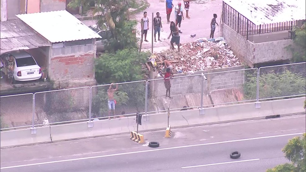 Homens atiram pneus na Linha Amarela, para impedir a passagem dos motoristas (Foto: Reprodu&ccedil;&atilde;o/ TV Globo)