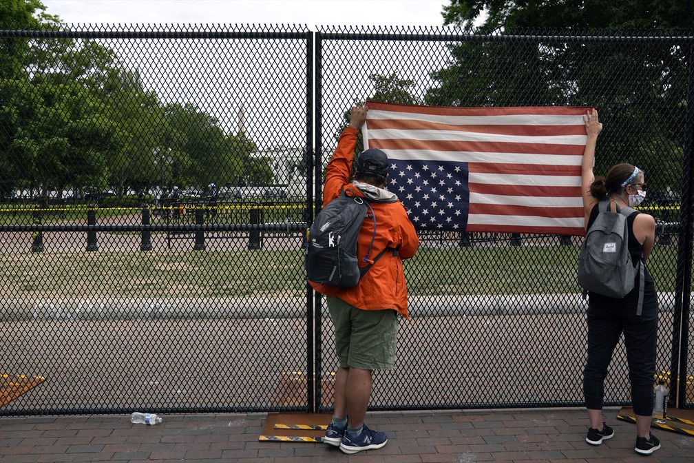 Manifestantes penduram bandeira dos EUA de cabeça para baixo em cerca em frente à Casa Branca, em Washington, nesta terça (2) — Foto: Evan Vucci/AP Photo