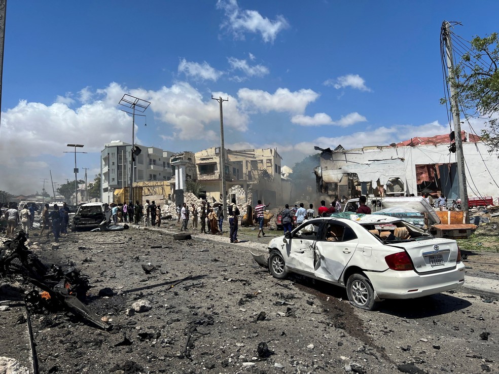 Pessoas observam veículos destruídos no local de uma explosão perto do aeroporto de Mogadíscio, capital da Somália, em janeiro de 2022 — Foto: Feisal Omar/Reuters