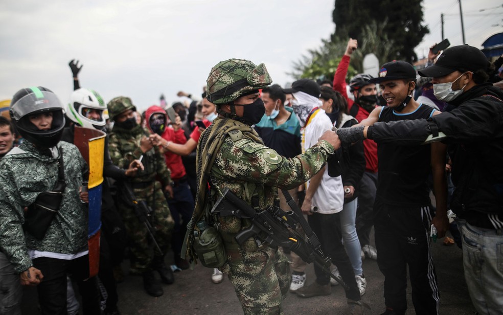 Manifestantes cumprimentam soldado durante protesto contra o governo em Madrid, na periferia de Bogotá, na Colômbia, na sexta-feira (28) — Foto: AP Photo/Ivan Valencia