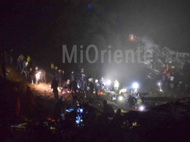 Imagem disponibilizada por um portal de notícias local mostra equipes em busca de sobreviventes e os destroços do avião ao fundo (Foto: Reprodução/Mi Oriente)