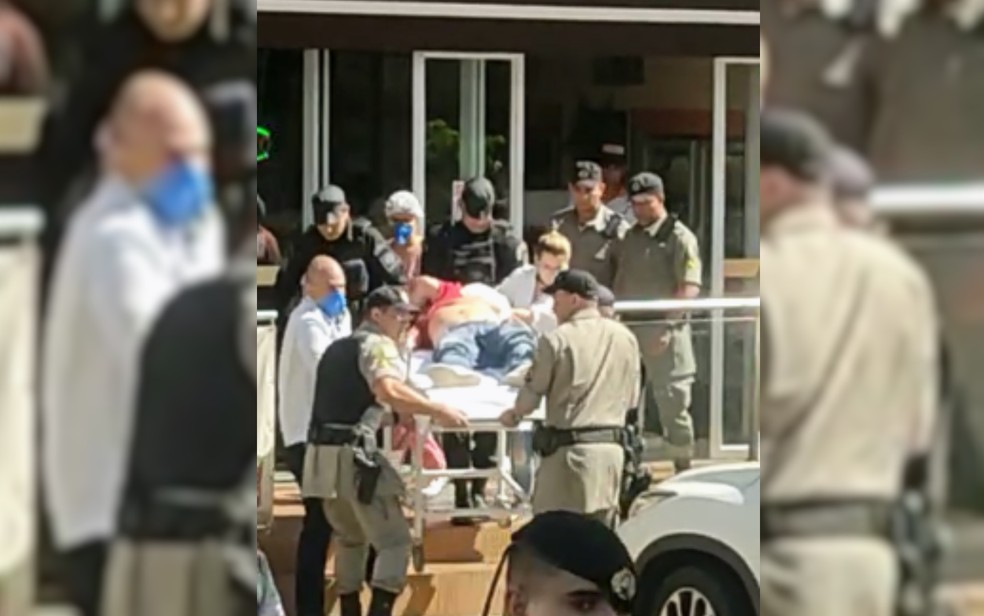 Homem baleado em farmácia é levado a hospital em maca por policiais e enfermeiros, em Goiânia, Goiás — Foto: Reprodução/TV Anhanguera