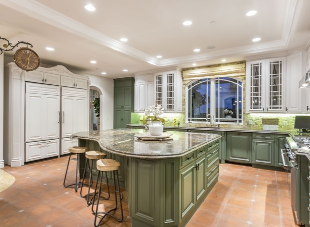 Na cozinha, os armários verdes se destacam sob a bancada de granito (Foto: Sotheby’s International Realty/ Reprodução)