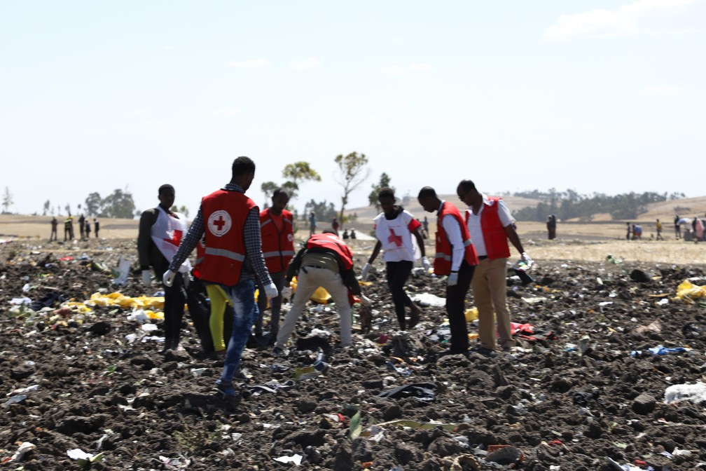 Trabalho da equipe da Cruz Vermelha em meio a destroços no local do acidente com avião na Etiópia — Foto: Michael Tewelde / AFP