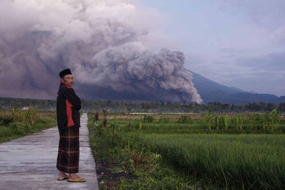 Um homem observa como o Monte Semeru joga material vulcânico no ar durante uma erupção no domingo, 4 de dezembro de 2022, em Lumajang, na Indonésia — Foto: AP