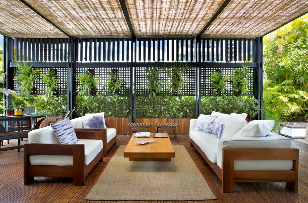 O pergolado de madeira projetado pelo arquiteto Jorge Hue recebeu treliças para minimizar o vento e a maresia. A paisagista Anna Luiza Rothier aproveitou a estrutura lateral como suporte para bromélias, orquídeas e samambaias — Foto: Juliano Colodeti /MCA Estúdio